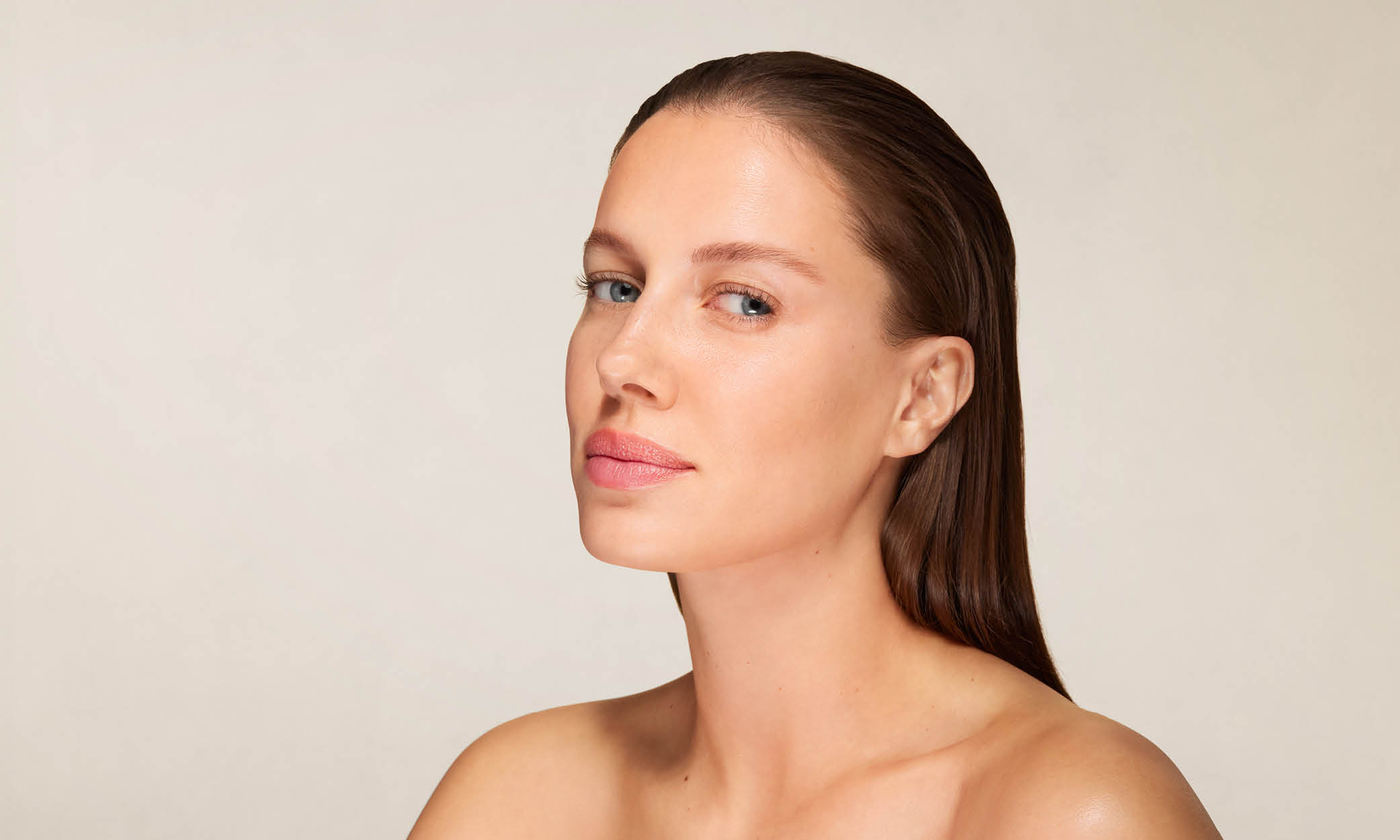 Frau mit glatter Haut und zurückgekämmtem Haar blickt leicht seitlich