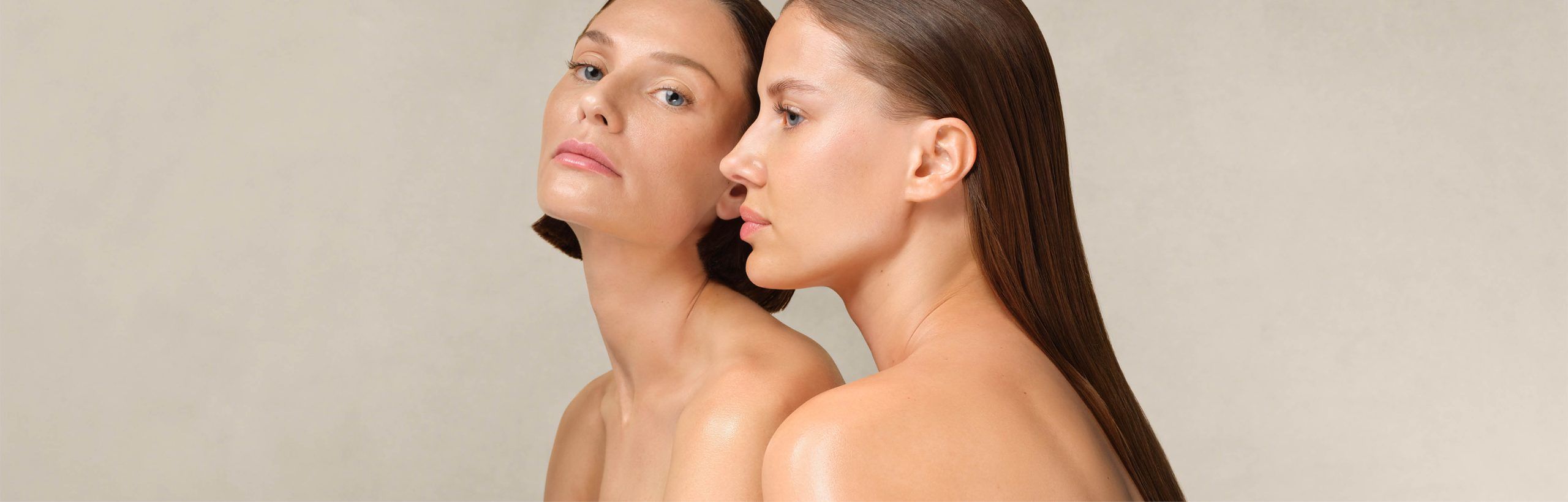 Zwei Frauen mit glatter Haut und zurückgekämmtem Haar, eine blickt frontal, die andere im Profil