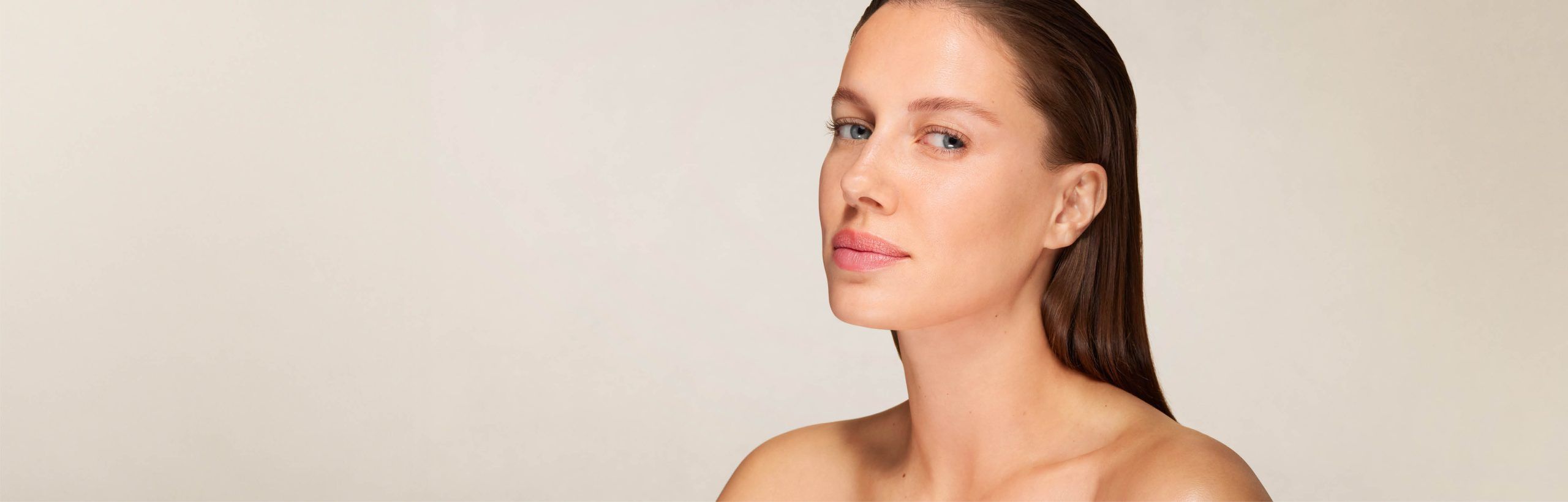 Frau mit glatter Haut und zurückgekämmtem Haar blickt leicht seitlich